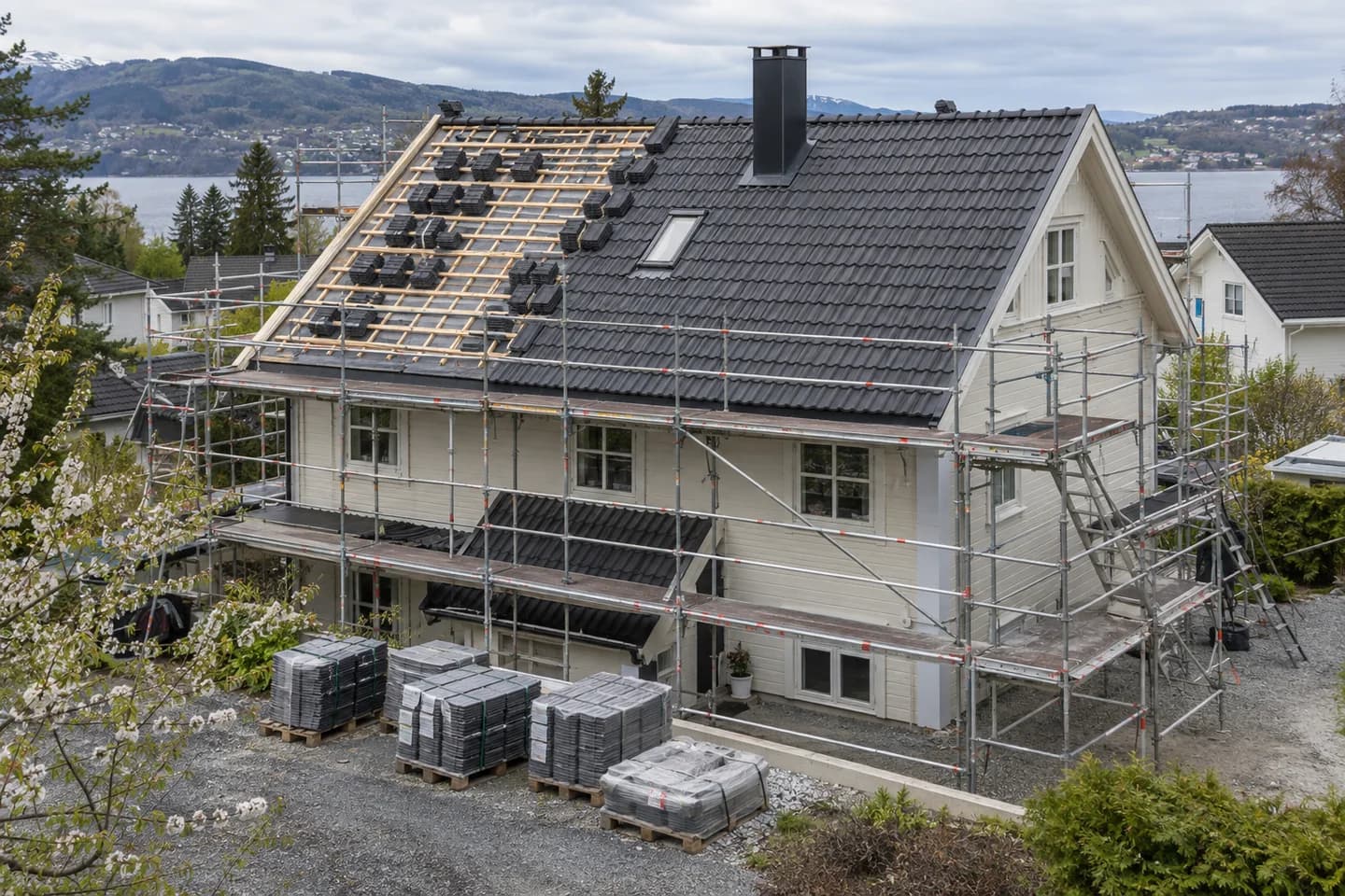 Illustrasjon: Takbytte på en lys villa med stillas og materialer på gårdsplassen